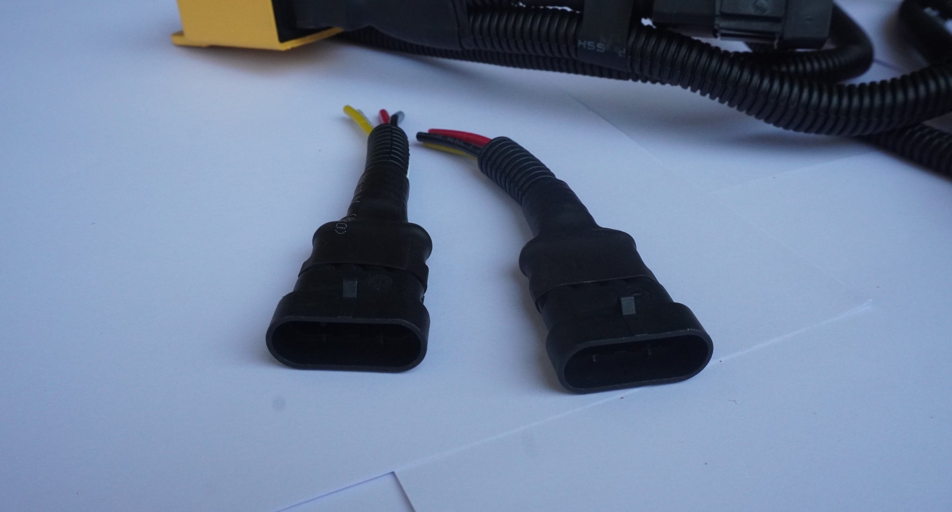 Two black electrical connectors on a white surface