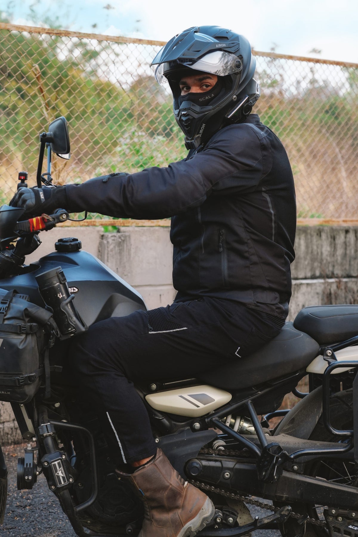 Side view of a seated motorcycle rider wearing Genesis 2.0 black jeans with reflective thigh and lower-leg detailing | MotoARZT