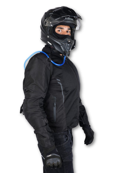 Shift-Pack_07.jpg: Side view of a helmeted rider wearing the Rollin’Denims Shift-Pack, with a blue hydration tube over the shoulder, at MotoARZT.